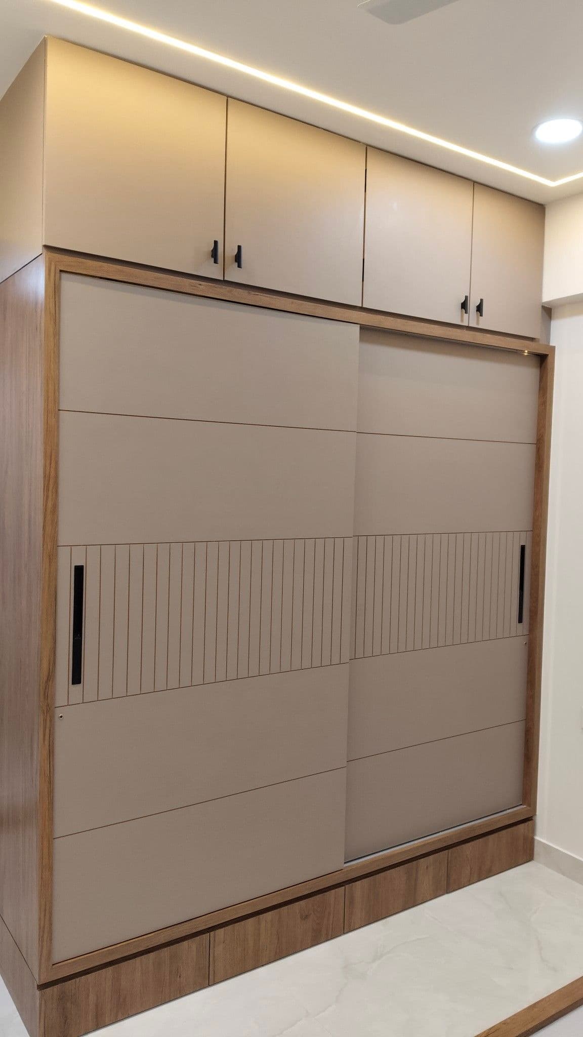 Modern floor-to-ceiling sliding wardrobe with neutral panels and wooden framing