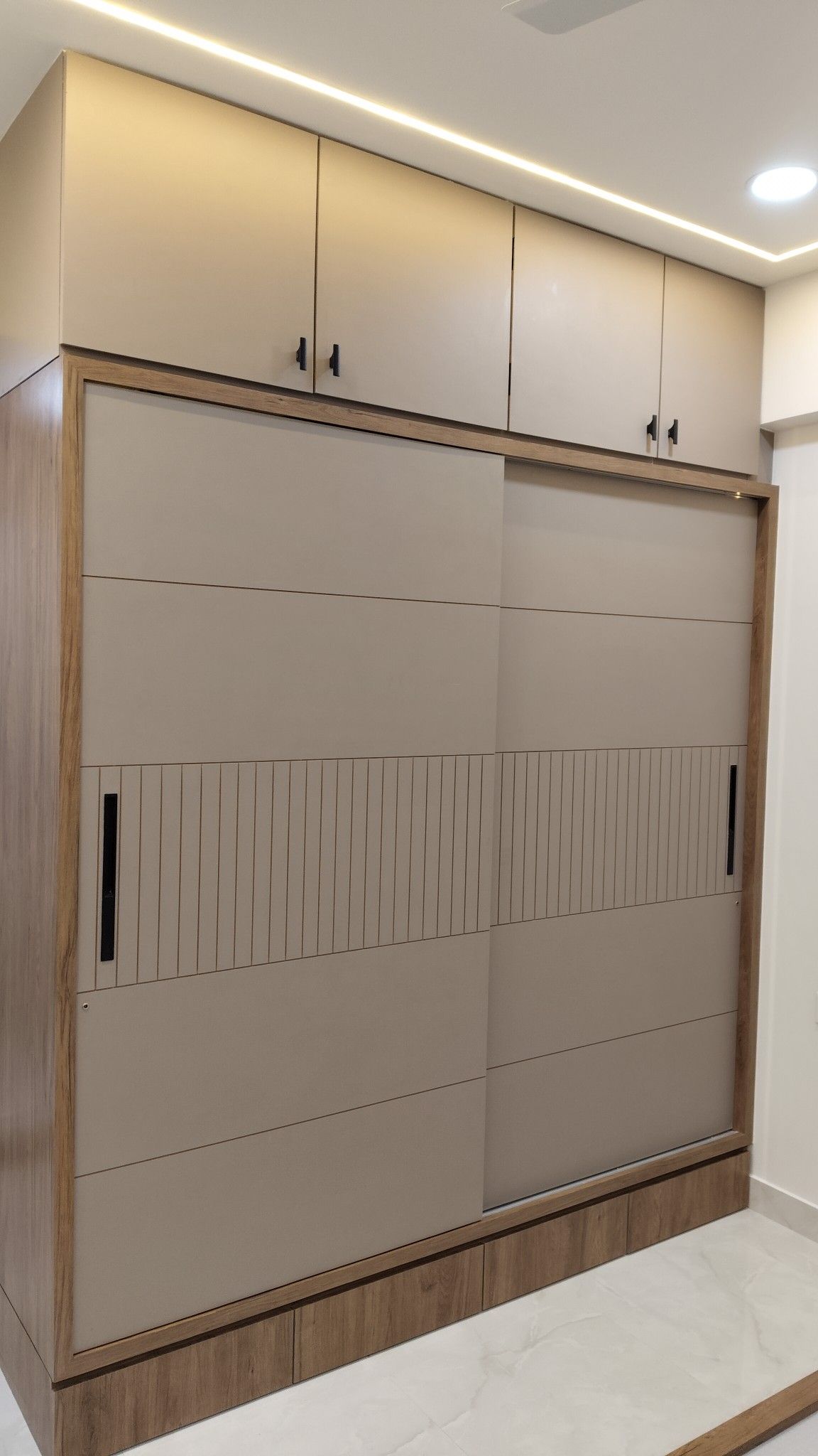 Modern floor-to-ceiling sliding wardrobe with neutral panels and wooden framing
